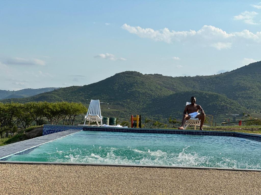 un hombre sentado en una silla junto a una piscina en Canal View Estate & Resort en Manzini