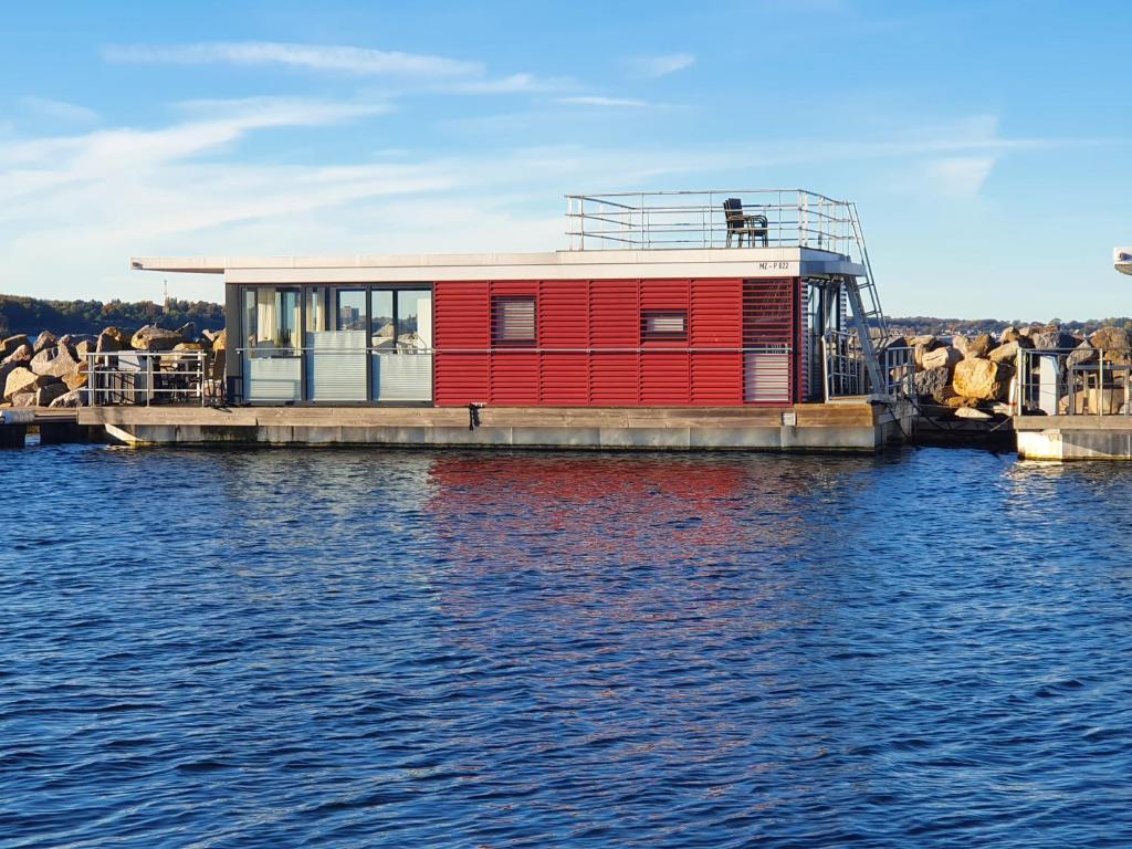 una casa roja en un muelle sobre el agua en Hausboot Floating 44 in Laboe - Boot 3 en Laboe