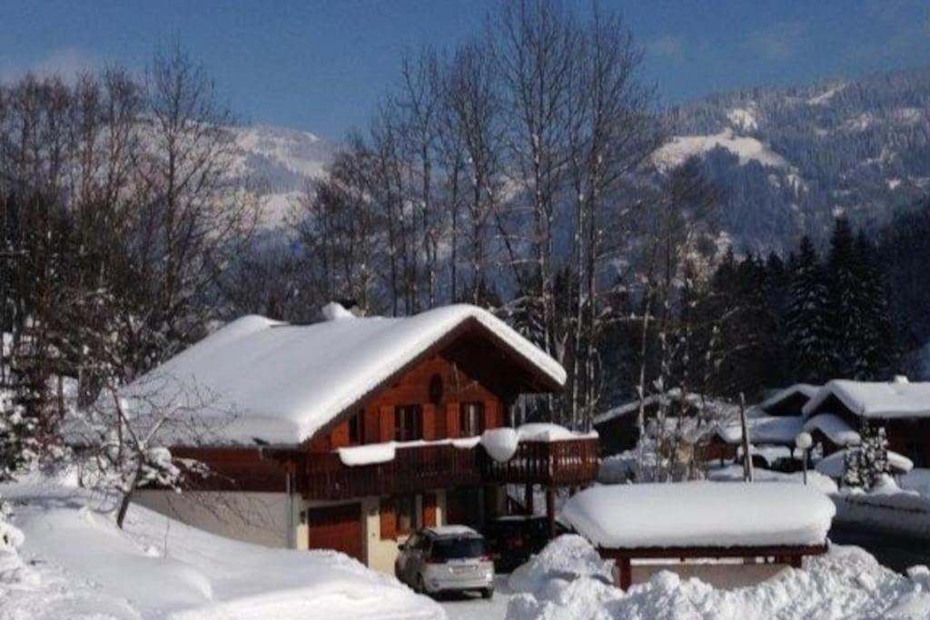 une maison recouverte de neige avec une voiture garée devant dans l'établissement Chalet Chocolat Chatel, à Châtel