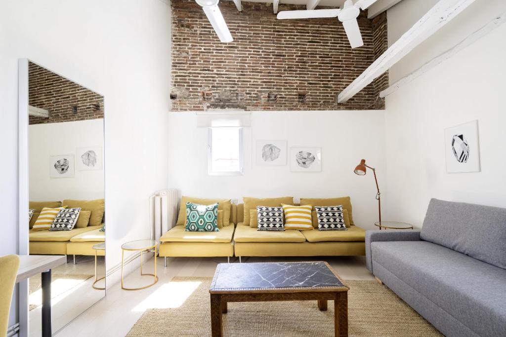 un soggiorno con divani e un muro di mattoni di apartamento el barrio de lavapies a Madrid