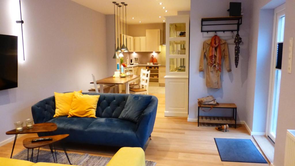 a living room with a blue couch and a kitchen at City Studio Kormoran in Bremerhaven