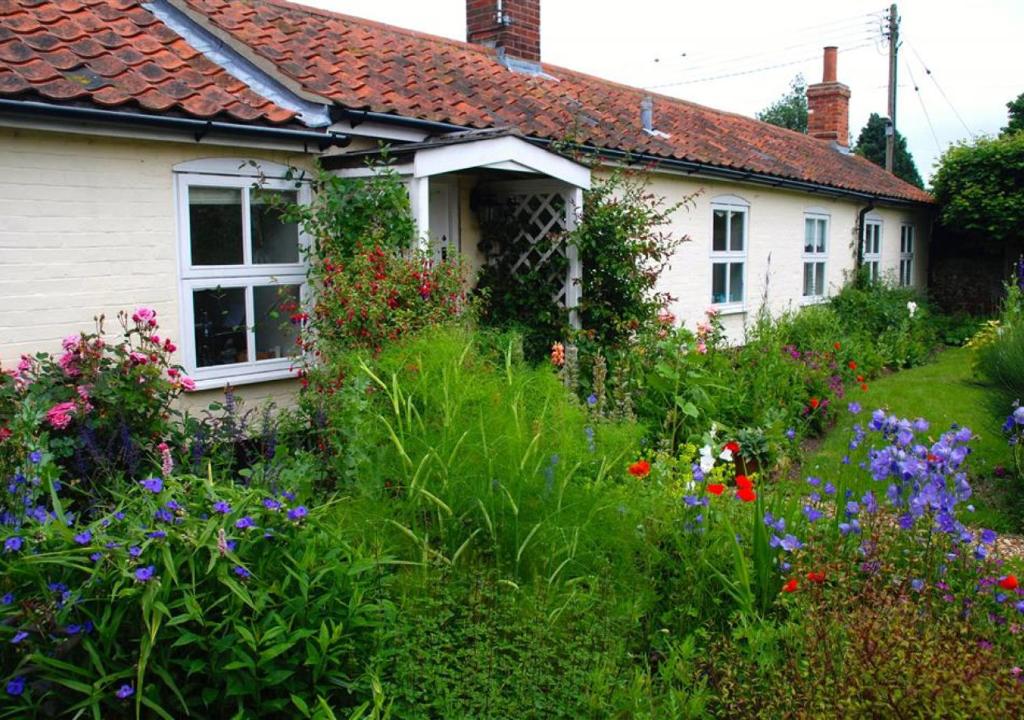 a garden in front of a house with flowers at Miller's Cottage, The Old Mill in Snape