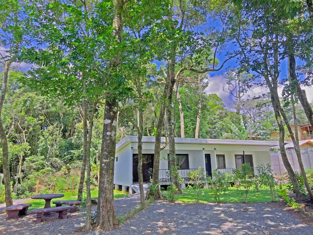 a white house with a picnic table and trees at Monteverde Magic Mountain in Monteverde Costa Rica