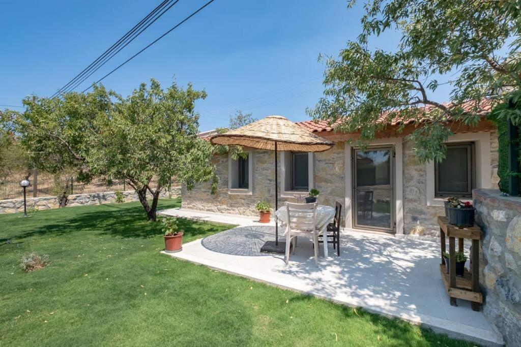 a house with a table and an umbrella in the yard at Stone Mini House Datça in Datca