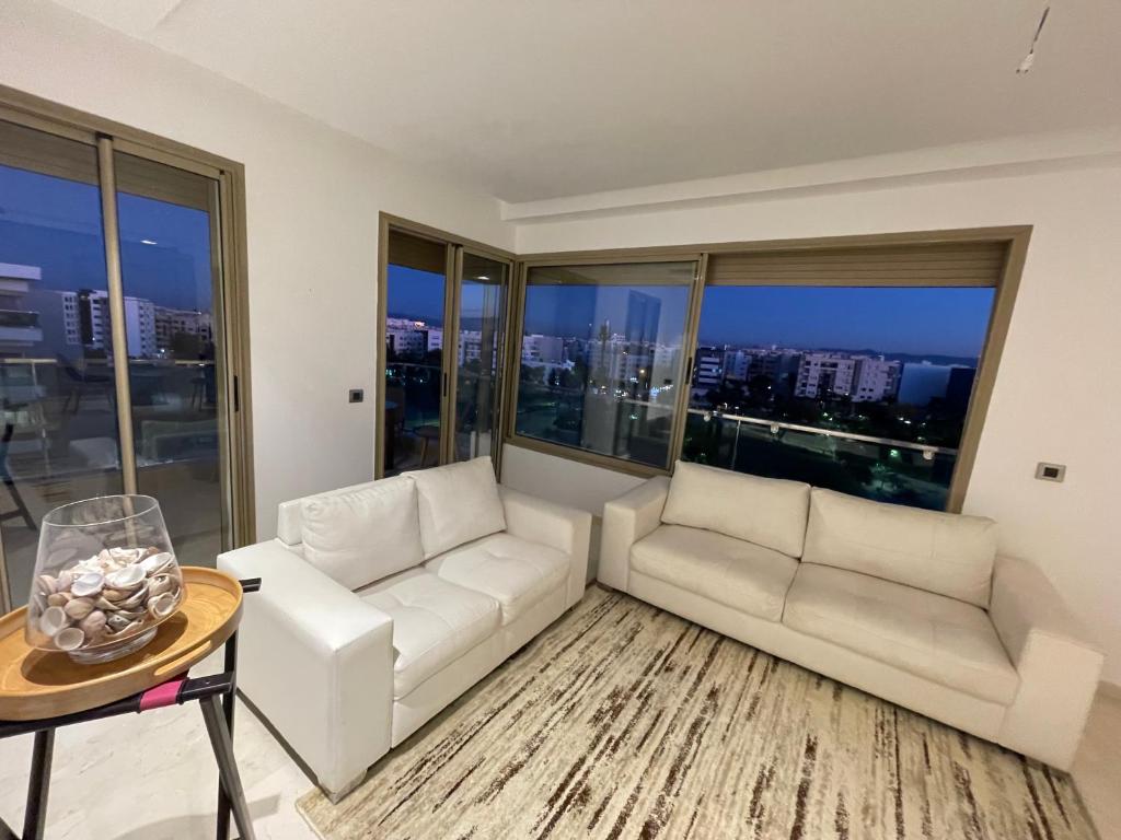 a living room with a white couch and a table at Appartement à louer avec une vue panoramique sur le parc prestigia fes in Fès