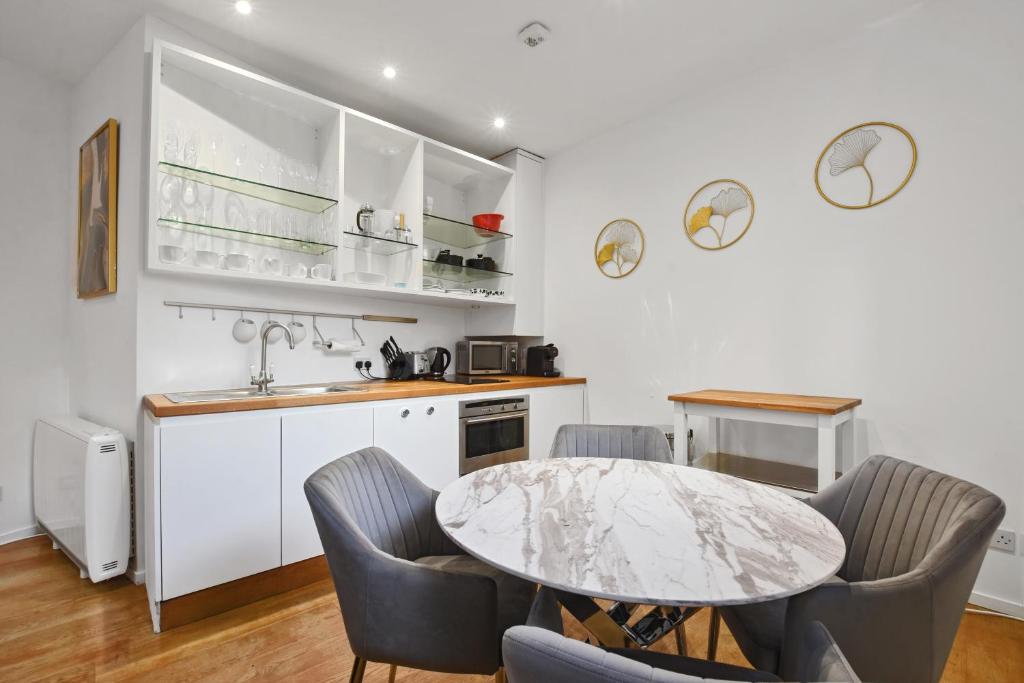 a kitchen with a table and chairs and a sink at The Mews Apartment In Kensington in London