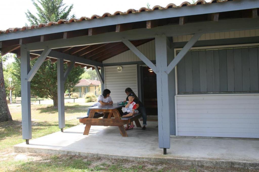 zwei Frauen sitzen an einem Picknicktisch unter einem Pavillon in der Unterkunft Les bruyeres in Brocas