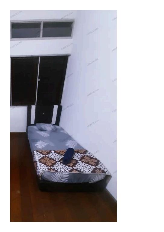 uma pequena cama num quarto com piso em madeira em AABM DELIMA HOMESTAY em Ipoh