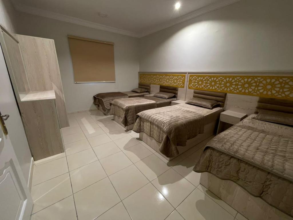 a room with four beds and a board on the wall at شقه راقيه سويت قريبه من المسجد النبوي تتسع لاربع اشخاص in Al Madinah