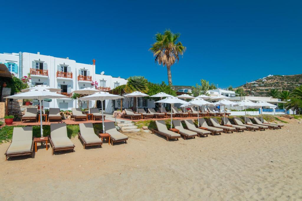 una fila di sedie a sdraio e ombrelloni in spiaggia di Hotel Efrosini a Platis Yialos Sifnos