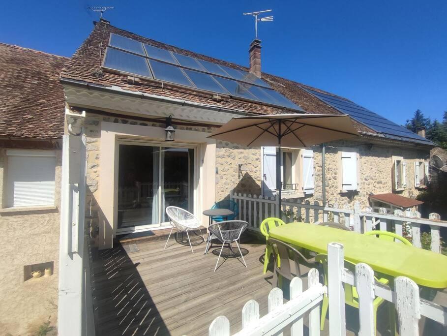 une terrasse en bois avec une table et un parasol dans l'établissement Gîte rural le Rouchassier, à Saint-Laurent-du-Cros