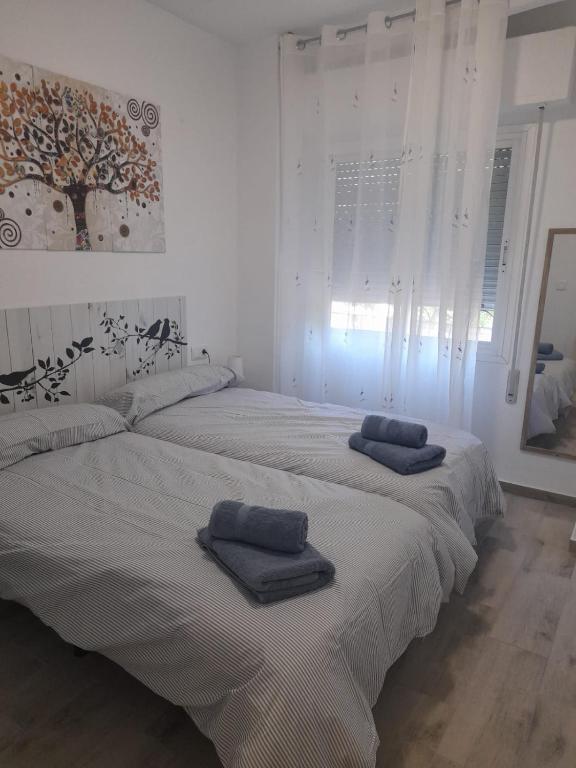two beds in a white room with towels on them at Paisaje Príncipe in Alcantarilla