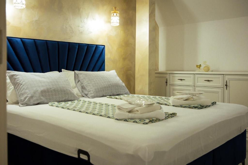 a bed with a blue headboard and towels on it at Kasa Nouveau in Oradea