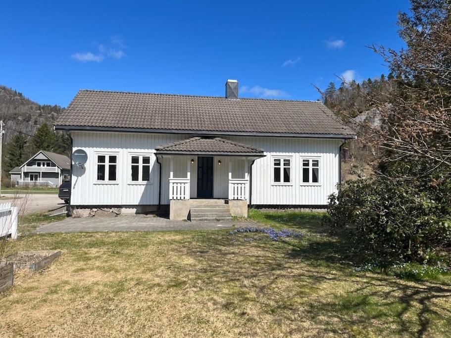 una pequeña casa blanca con una puerta negra en sjarmerende gardshus en Hægebostad