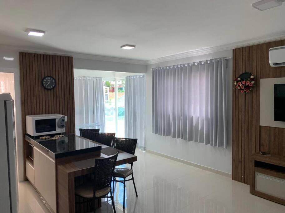 a kitchen with a table and chairs and a microwave at Lindo Apto NOVO na Avenida, climatizado e aconchegante in Piratuba