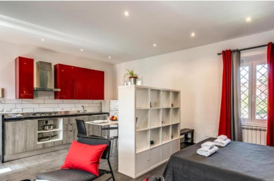 uma cozinha com armários vermelhos e uma cama num quarto em Appartamento dell'acquedotto romano em Roma