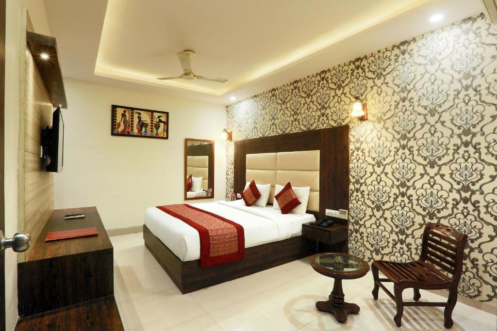 a hotel room with a bed and a chair at Hotel Red Velvet Suites At Delhi Airport in New Delhi