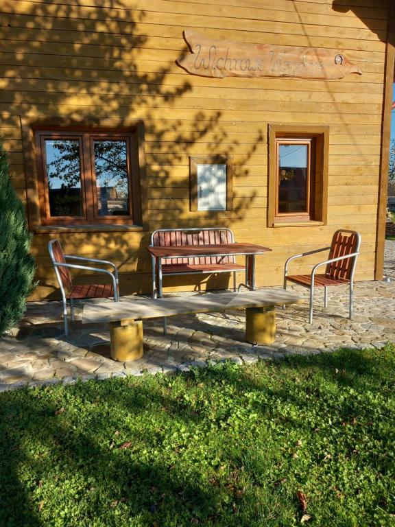 eine Terrasse mit 2 Stühlen, einem Tisch und 2 Bänken in der Unterkunft Wichrowe Wzgórze in Dynów