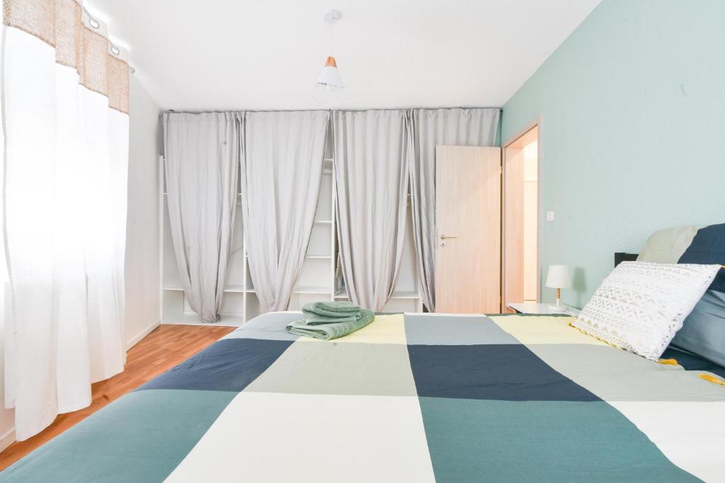 ein Schlafzimmer mit einem Bett mit einer blauen und weißen Decke in der Unterkunft Evasion Mulhousienne in Mulhouse