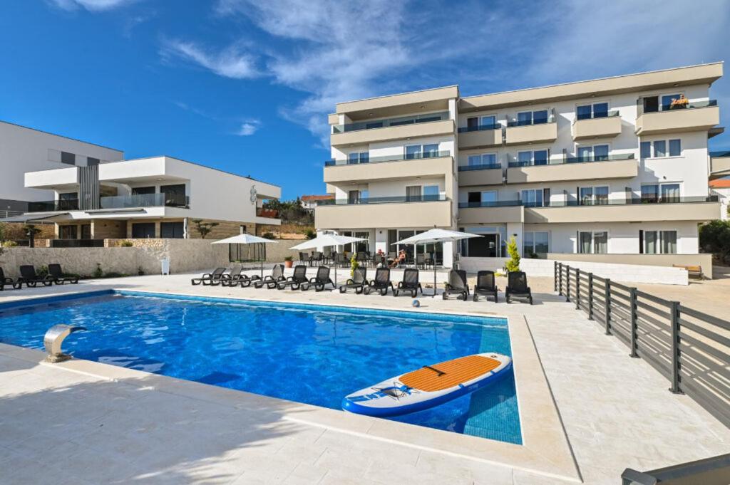 a swimming pool with a surfboard in front of a building at Boutique Hotel IVY'Z in Novalja