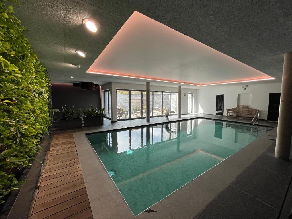 a large swimming pool in a building with a ceiling at Hotel Côté Cour in Durbuy