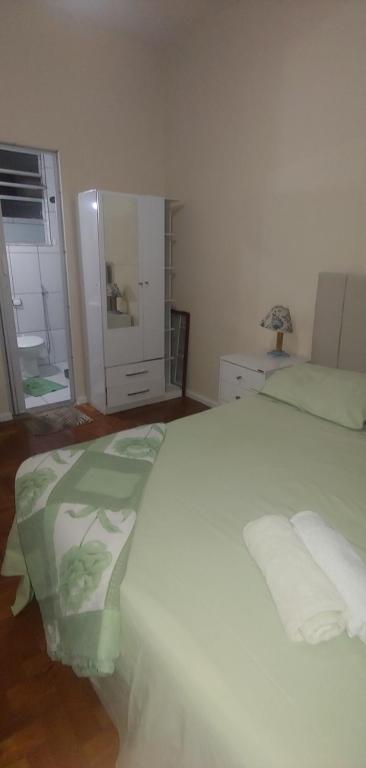 1 dormitorio con 1 cama blanca con manta verde en Studio Copacabana, en Río de Janeiro
