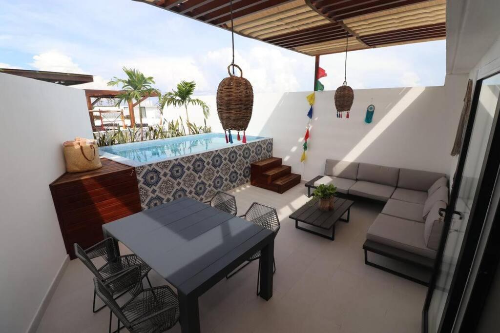 ein Wohnzimmer mit einem Tisch und einem Pool in der Unterkunft Amazing!! PH 2 Bdrm + Private Rooftop &Pool /Aldea Zama in Tulum