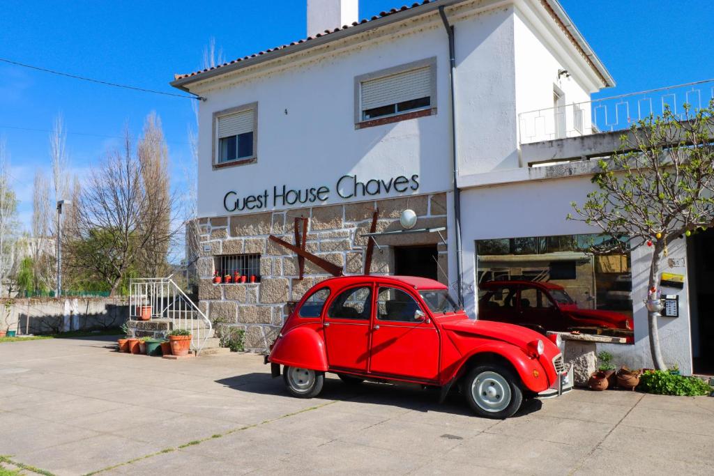 een oude rode auto geparkeerd voor een huis bij Guest House Chaves in Chaves