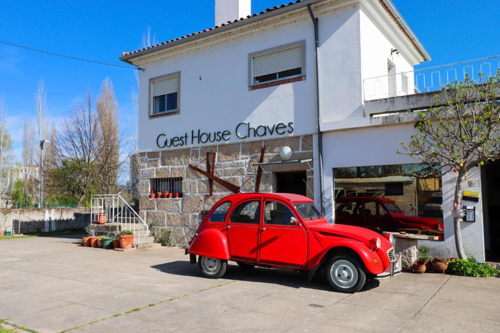 une vieille voiture rouge garée devant une maison dans l'établissement Guest House Chaves, à Chaves