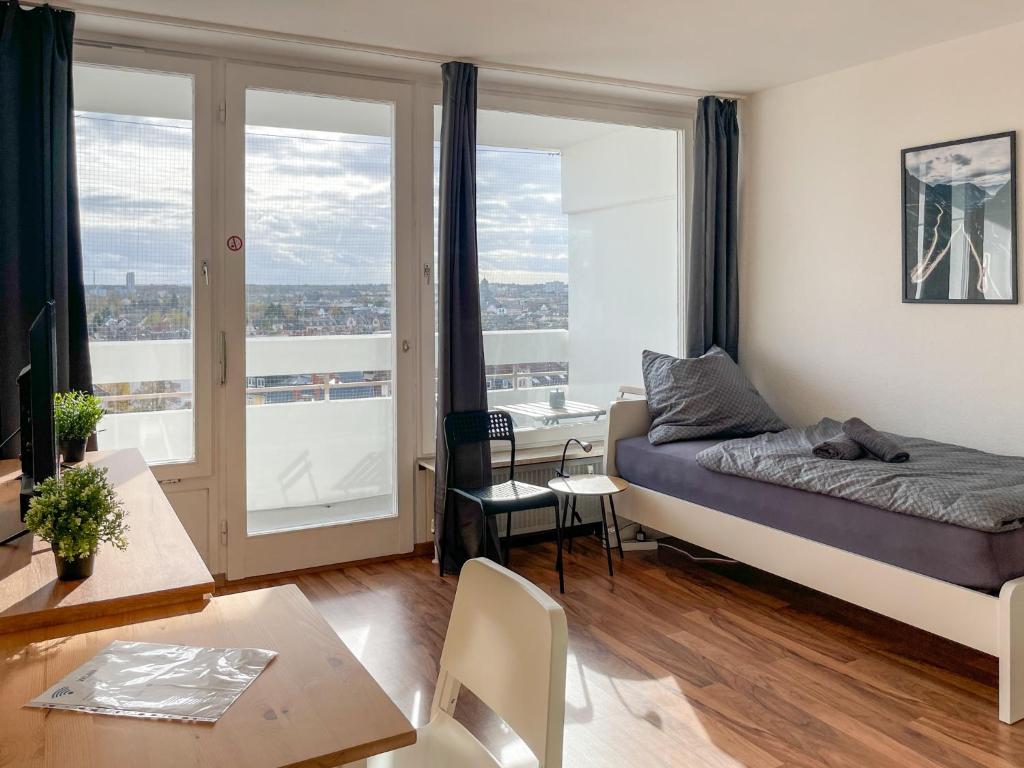 Cosy flat with stunning view في أوفنباخ: غرفة نوم بسرير وطاولة وغرفة بها نوافذ