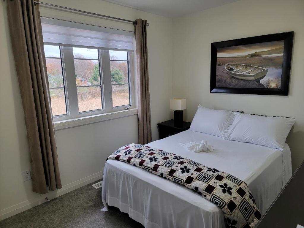 Schlafzimmer mit einem Bett und einem Fenster in der Unterkunft Chorburjo Cozy Villa - Two Rooms in Penetanguishene