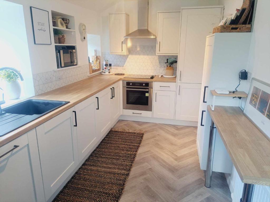 a kitchen with white cabinets and a wooden floor at Cliff Cottage in Valtos
