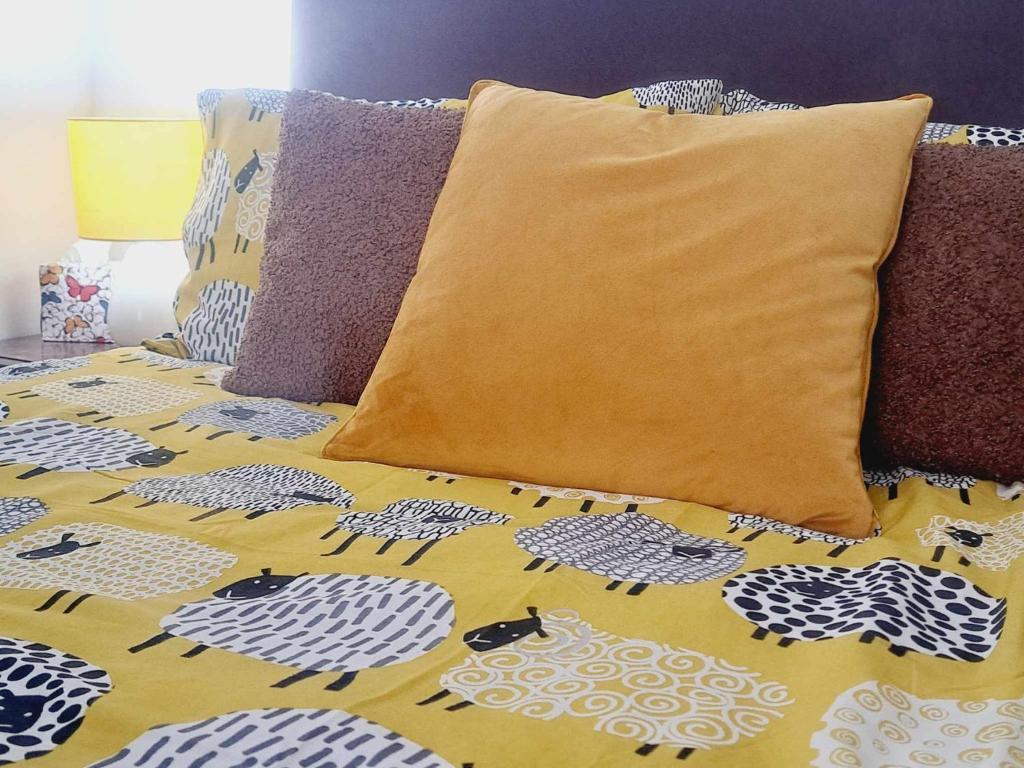 a bed with a yellow and white bedspread with pillows at Cliff Cottage in Valtos
