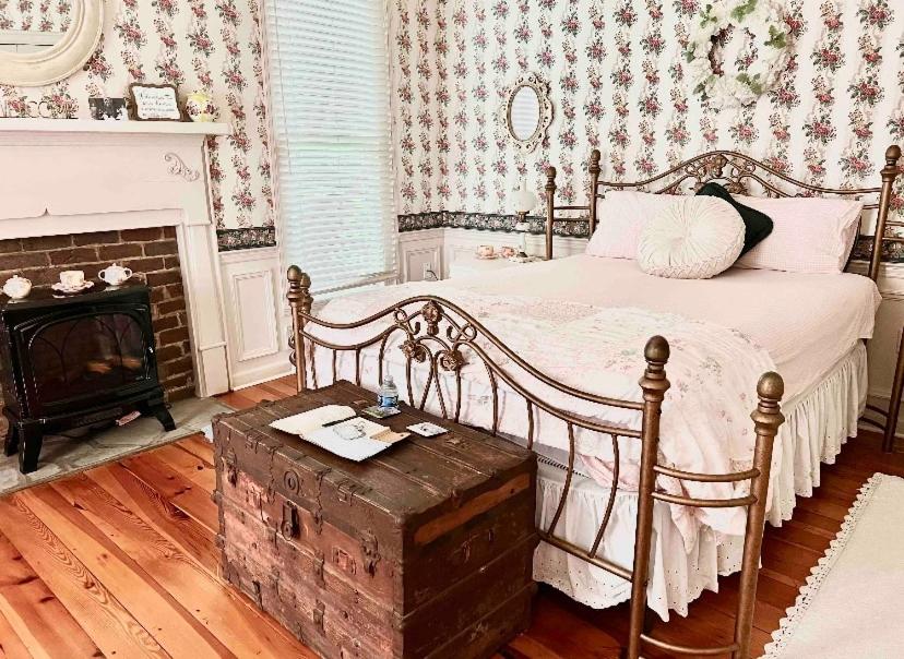 ein Schlafzimmer mit einem Bett mit einer Holzkiste neben einem Kamin in der Unterkunft Historic Seaton Springs Farm B&B - M Seaton Queen Room with Private Bath down the hall in Sevierville