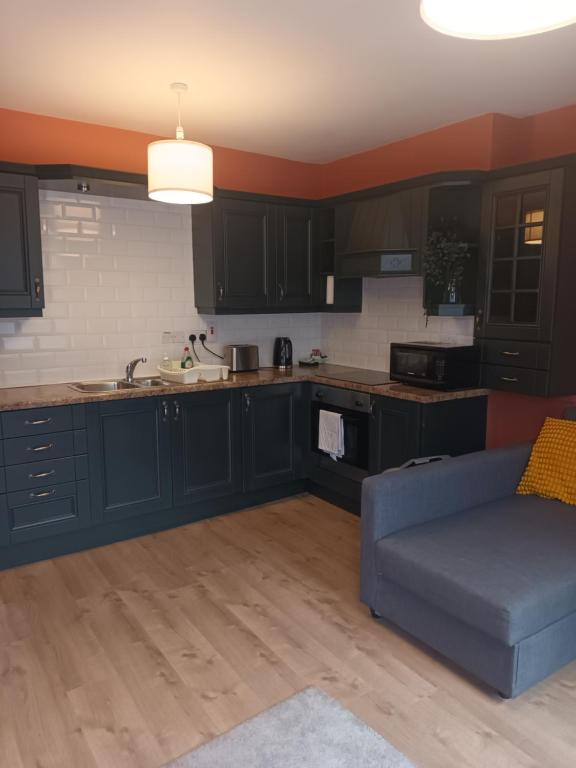 a kitchen with black cabinets and a blue couch at Belle View Apartment #4 in Newcastle