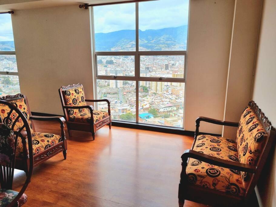 a living room with two chairs and a large window at apartamento con vista volcán in Pasto