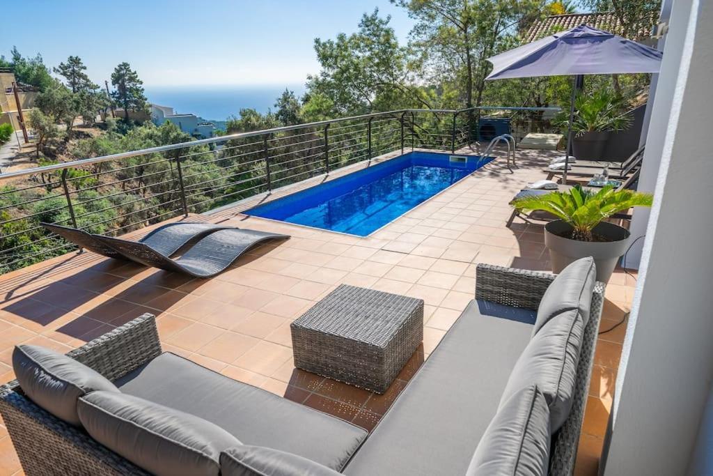 een balkon met een zwembad, een bank en een parasol bij Villa Lovely Breeze, heerlijk familiehuis, 7pers. in Lloret de Mar
