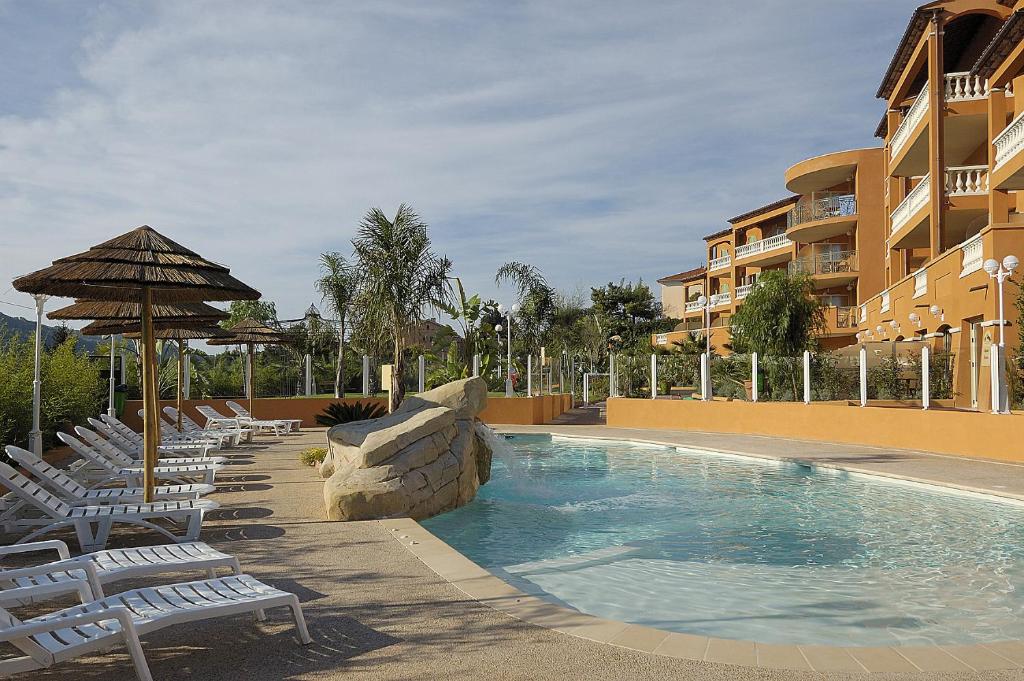 uma piscina com espreguiçadeiras e um guarda-sol em Appart Hotel Lou Castelet em Carros