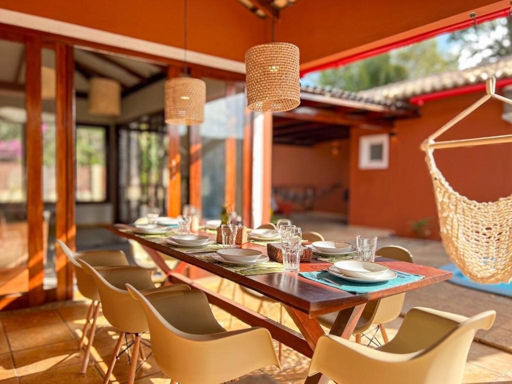 uma sala de jantar com uma mesa longa e cadeiras em Casa Sapoti - 3 Suítes no centro em Pipa