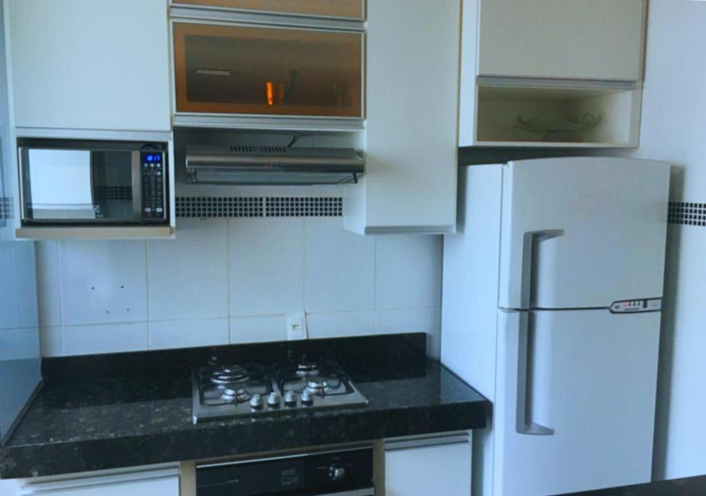 a kitchen with a stove and a microwave and a refrigerator at Elegância e Conforto no Centro da Cidade in Vespasiano