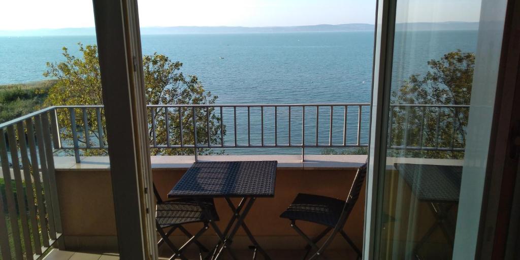 ein Tisch und zwei Stühle auf einem Balkon mit Blick auf das Meer in der Unterkunft Piroska Wellness Apartman Siófok in Siófok