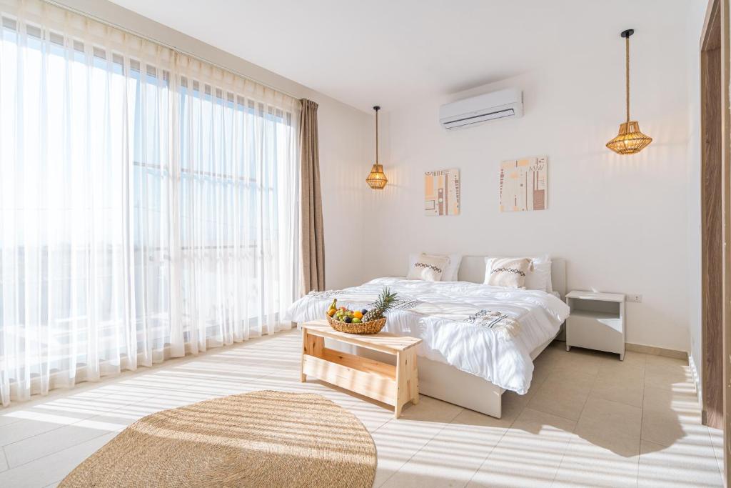 Dormitorio blanco con cama y mesa en Nammos Experience en Amán