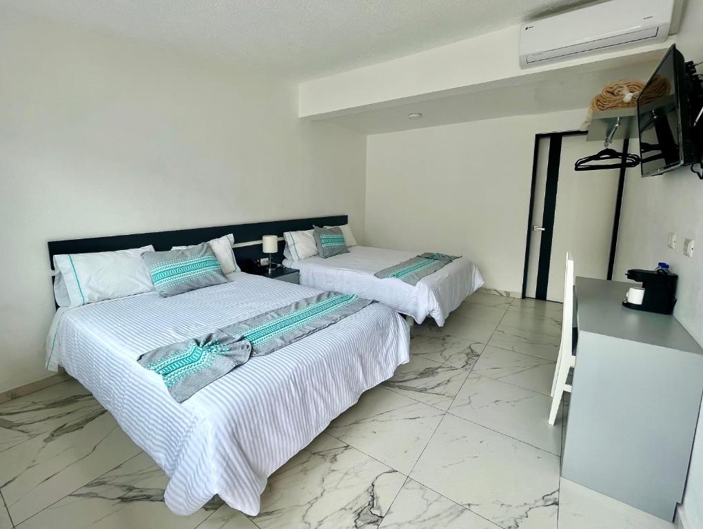 two beds in a room with white walls and marble floors at Villa Santa Julia in Oaxaca City