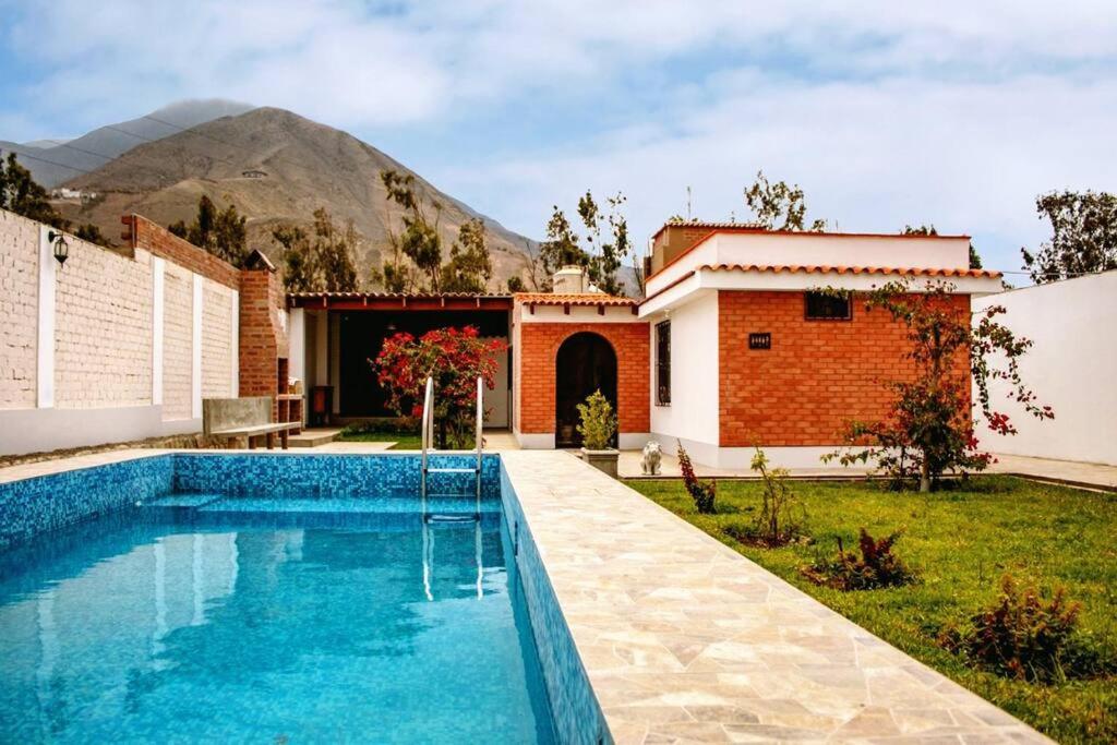 una piscina frente a una casa con una montaña en el fondo en Amplia Casa de Campo con Piscina en Cieneguilla en Cieneguilla