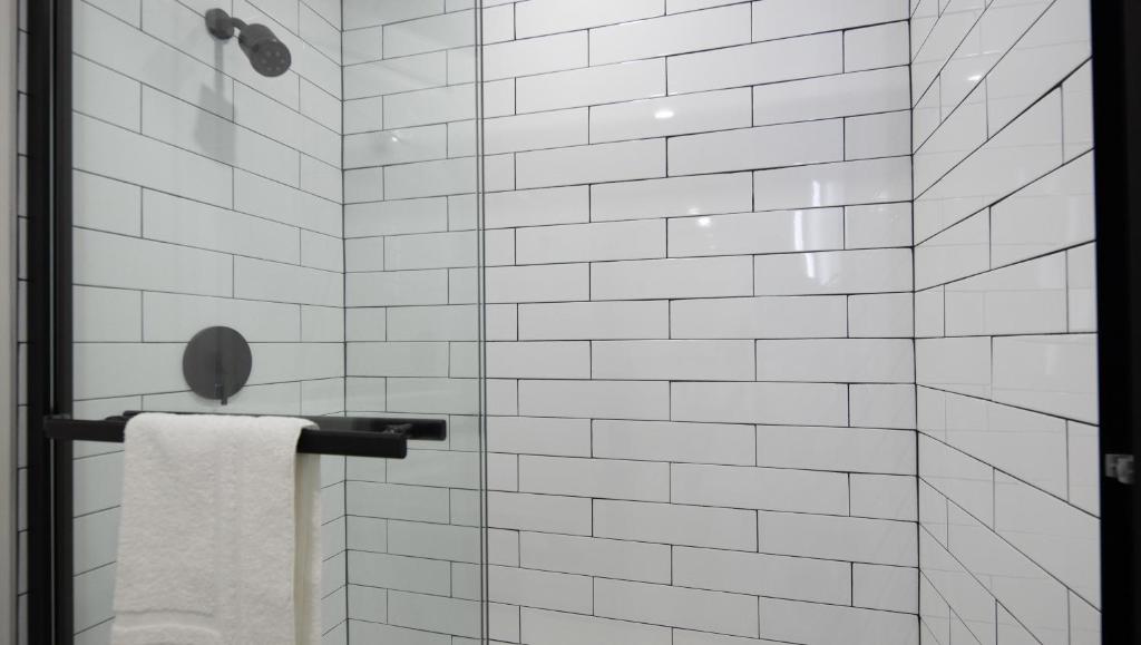 Una ducha con azulejos blancos y un toallero en el toallero. en The Catrina Hotel, en San Mateo