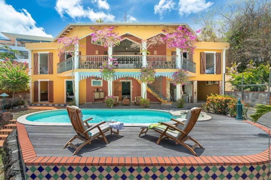 une villa avec une piscine et deux chaises dans l'établissement Villa Sol Y Sombra, à Schœlcher