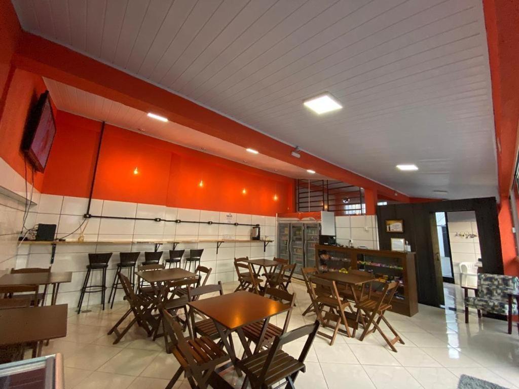 ein Restaurant mit Holztischen und -stühlen und orangefarbenen Wänden in der Unterkunft Pousada355 in Passo Fundo