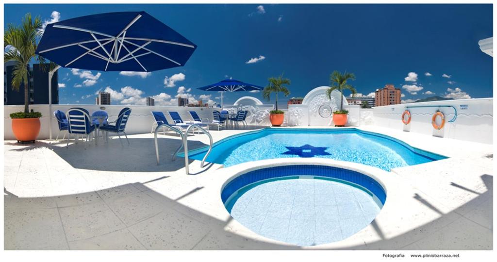 a swimming pool with chairs and an umbrella at Hotel Buena Vista in Bucaramanga