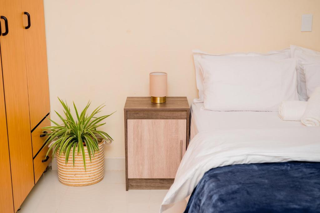 sypialnia z łóżkiem i stolikiem nocnym z rośliną w obiekcie Davi Bliss w mieście Oshakati