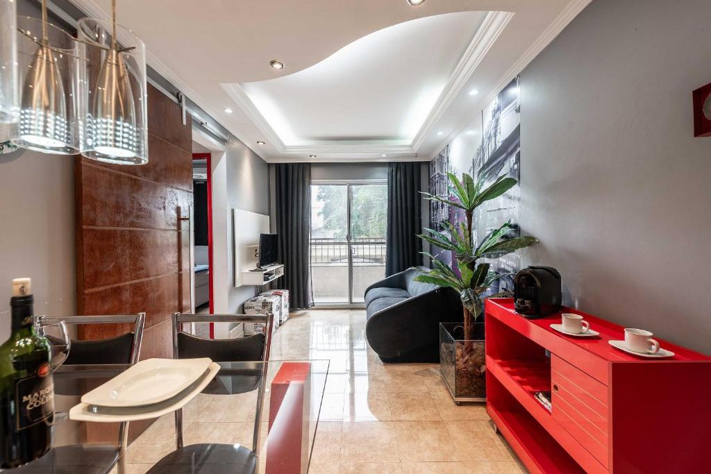 uma sala de estar com uma mesa vermelha e cadeiras em SA11 - Apto 2 Dorms Totalmente Equipado e Acolhedor em São Paulo